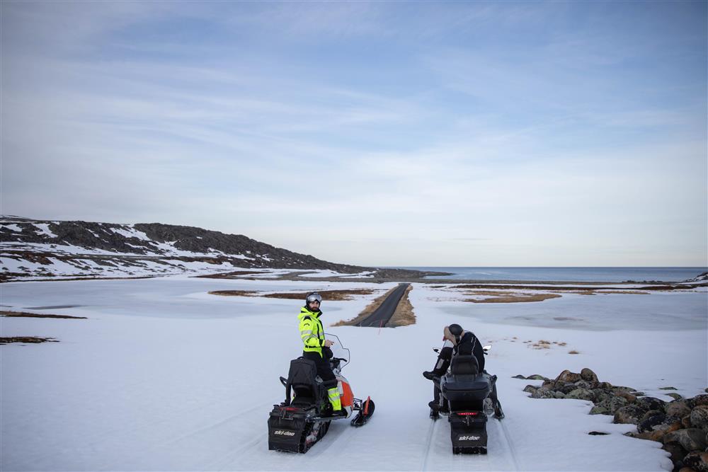 To skutere med førere ser mot en strekke landevei på vinterstid. - Klikk for stort bilde