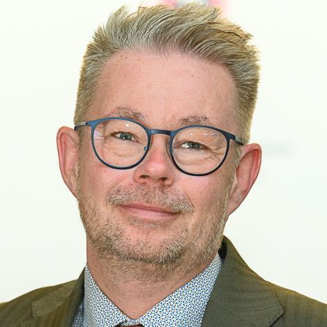Mann med blå briller,  lett skjegg og blond-grått hår i dress - Klikk for stort bilde